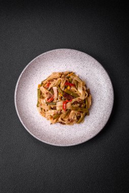 Lezzetli Asya yemeği udonu acı biber, yeşil fasulye, baharat ve otlar seramik tabakta koyu beton arka planda.