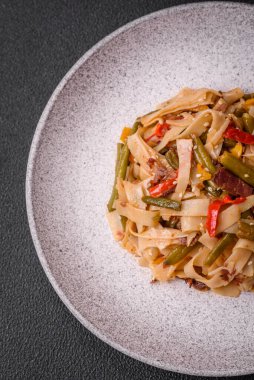 Lezzetli Asya yemeği udonu acı biber, yeşil fasulye, baharat ve otlar seramik tabakta koyu beton arka planda.