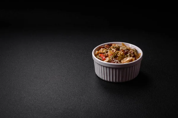 stock image Delicious Asian dish udon with hot peppers, green beans, spices and herbs on a ceramic plate on a dark concrete background