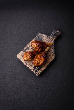 Lezzetli ızgara tavuk bacağı. Baharatlı ve otlu teriyaki soslu. Koyu beton arka planda.