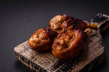 Lezzetli ızgara tavuk bacağı. Baharatlı ve otlu teriyaki soslu. Koyu beton arka planda.