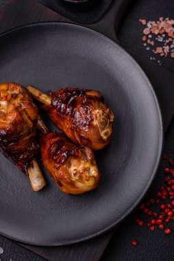 Lezzetli ızgara tavuk bacağı. Baharatlı ve otlu teriyaki soslu. Koyu beton arka planda.