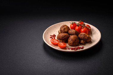 Izgarada pişirilmiş lezzetli sulu şampiyonlar koyu beton arka planda seramik tabakta tuz ve baharatlarla.