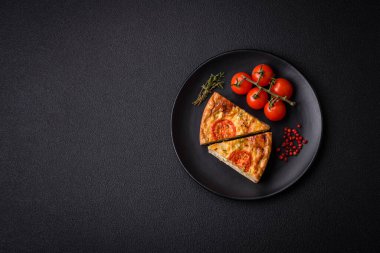 Koyu beton arka planda domates, peynir, tavuk, baharat ve bitkilerle nefis kiş.