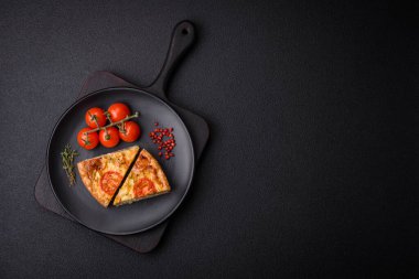 Koyu beton arka planda domates, peynir, tavuk, baharat ve bitkilerle nefis kiş.