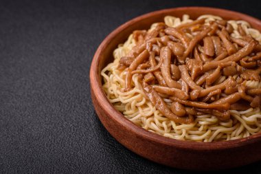 Lezzetli Asya mutfağı. İçinde pirinç, erişte, biber, mantar ve baharatlar var. Koyu beton arka planda.