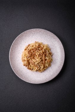 Lezzetli Asya mutfağı. İçinde pirinç, erişte, biber, mantar ve baharatlar var. Koyu beton arka planda.