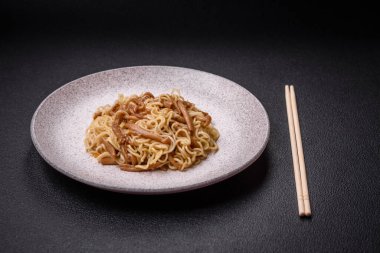 Lezzetli Asya mutfağı. İçinde pirinç, erişte, biber, mantar ve baharatlar var. Koyu beton arka planda.