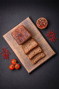 Koyu beton bir arka planda tohumları ve tahılları olan lezzetli çıtır çıtır kahverengi ekmek.