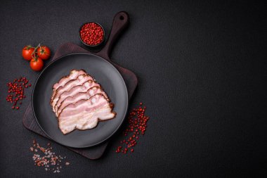 Lezzetli taze pancetta ya da tuzlu ve baharatlı pastırma koyu beton arka planda ince dilimler halinde kesilmiş.