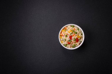 Lezzetli beyaz haşlanmış pirinç, sebzeli, tatlı biberli, havuçlu, bezelyeli, tuzlu ve baharatlı koyu beton arka planda.