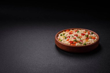 Lezzetli beyaz haşlanmış pirinç, sebzeli, tatlı biberli, havuçlu, bezelyeli, tuzlu ve baharatlı koyu beton arka planda.