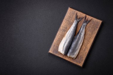 Pasifik ringa filetosu. Tuz, baharat ve otlarla marine edilmiş. Koyu beton arka planda.