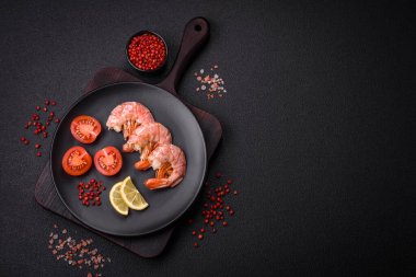Lezzetli karides veya langoustine kuyrukları koyu beton arka planda tuz ve baharatla kaynatılmış.