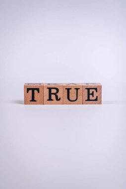 Düz arkaplandaki tahta küplerden yapılmış True yazısını. Tasarımınız için kullanılabilir