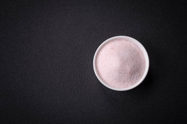 Himalaya 'nın ince pembe masa tuzu, koyu beton arka planda seramik bir kasede.