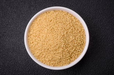 Koyu beton arka planda buğday lapası kuskus taneleri. Lezzetli, besleyici bir kahvaltı hazırlıyorum.