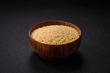 Koyu beton arka planda buğday lapası kuskus taneleri. Lezzetli, besleyici bir kahvaltı hazırlıyorum.