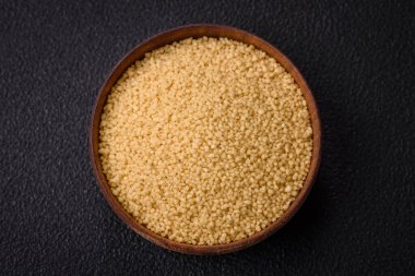 Koyu beton arka planda buğday lapası kuskus taneleri. Lezzetli, besleyici bir kahvaltı hazırlıyorum.