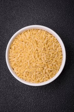 Ham risoni makarnası koyu beton arka planda buğdaydan yapılır. Lezzetli, besleyici bir kahvaltı hazırlıyorum.