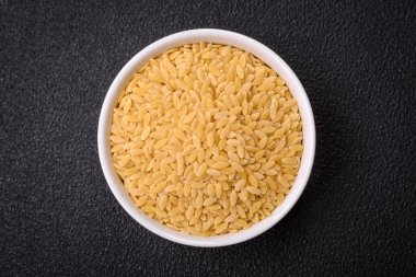 Ham risoni makarnası koyu beton arka planda buğdaydan yapılır. Lezzetli, besleyici bir kahvaltı hazırlıyorum.