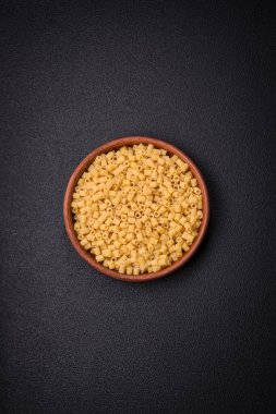 Ham ditali makarna, koyu beton arka planda buğdaydan yapılmış. Lezzetli, besleyici bir kahvaltı hazırlıyorum.