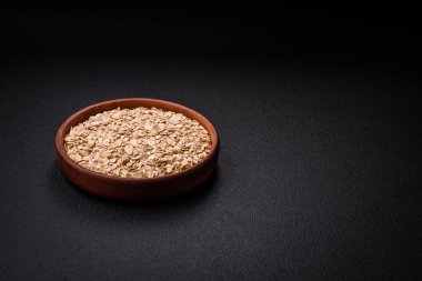 Seramik bir kasede koyu beton zeminde çiğ yulaf lapası. Lezzetli, besleyici bir kahvaltı hazırlıyorum.