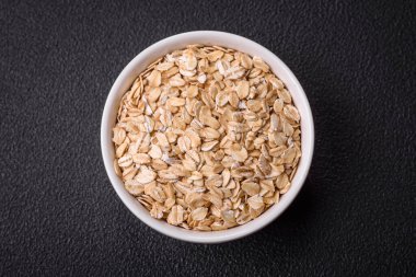 Seramik bir kasede koyu beton zeminde çiğ yulaf lapası. Lezzetli, besleyici bir kahvaltı hazırlıyorum.