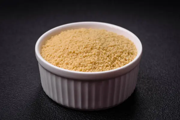 Koyu beton arka planda buğday lapası kuskus taneleri. Lezzetli, besleyici bir kahvaltı hazırlıyorum.