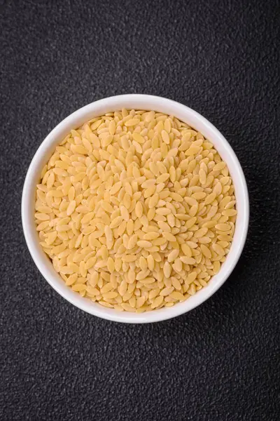 Ham risoni makarnası koyu beton arka planda buğdaydan yapılır. Lezzetli, besleyici bir kahvaltı hazırlıyorum.