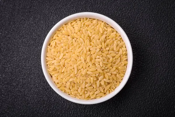 Ham risoni makarnası koyu beton arka planda buğdaydan yapılır. Lezzetli, besleyici bir kahvaltı hazırlıyorum.