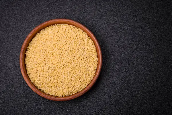 Ham risoni makarnası koyu beton arka planda buğdaydan yapılır. Lezzetli, besleyici bir kahvaltı hazırlıyorum.