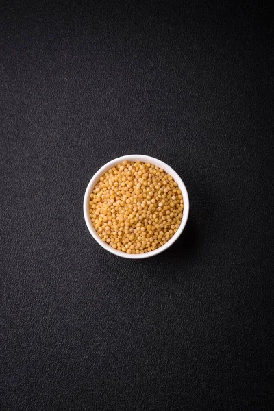 Koyu beton arka planda buğday lapası taneleri. Lezzetli, besleyici bir kahvaltı hazırlıyorum.