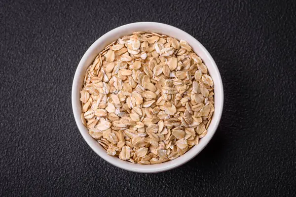 Seramik bir kasede koyu beton zeminde çiğ yulaf lapası. Lezzetli, besleyici bir kahvaltı hazırlıyorum.