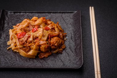 Sebzeli, mantarlı, tuzlu ve baharatlı lezzetli Asya udonu tabağı koyu beton arka planda.