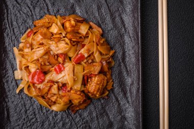 Sebzeli, mantarlı, tuzlu ve baharatlı lezzetli Asya udonu tabağı koyu beton arka planda.