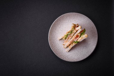 Tost ekmekli, jambonlu, domatesli, peynirli ve soslu lezzetli bir sandviç.