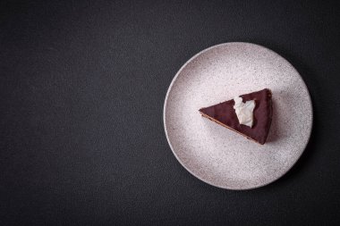 Koyu beton arka planda kremalı ve süngerli lezzetli çikolatalı pasta.