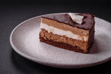 Koyu beton arka planda kremalı ve süngerli lezzetli çikolatalı pasta.