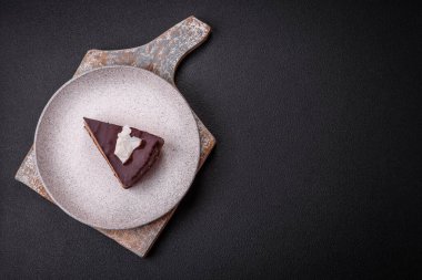 Koyu beton arka planda kremalı ve süngerli lezzetli çikolatalı pasta.