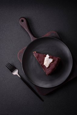 Koyu beton arka planda kremalı ve süngerli lezzetli çikolatalı pasta.