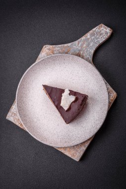 Koyu beton arka planda kremalı ve süngerli lezzetli çikolatalı pasta.