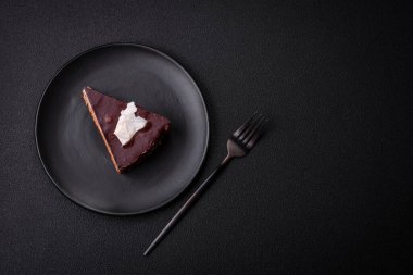 Koyu beton arka planda kremalı ve süngerli lezzetli çikolatalı pasta.