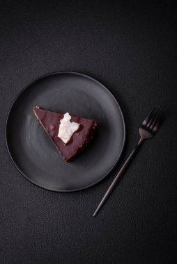 Koyu beton arka planda kremalı ve süngerli lezzetli çikolatalı pasta.