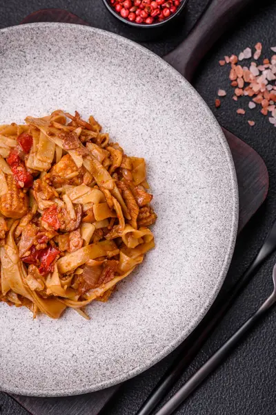 Sebzeli, mantarlı, tuzlu ve baharatlı lezzetli Asya udonu tabağı koyu beton arka planda.