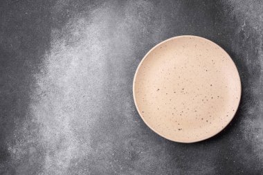 Açık desenli arka planda boş seramik tabak. Mutfak aletleri