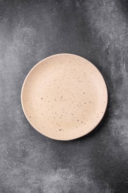 Açık desenli arka planda boş seramik tabak. Mutfak aletleri