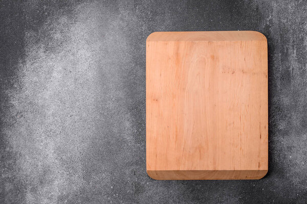 Empty wooden cutting board on a light texture background. Kitchen utensils
