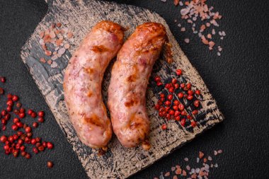 Lezzetli ızgara tavuk ya da koyu beton arka planda tuzlu ve baharatlı domuz sosisi.