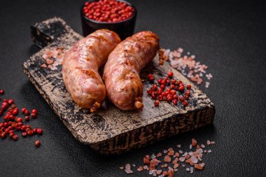 Lezzetli ızgara tavuk ya da koyu beton arka planda tuzlu ve baharatlı domuz sosisi.